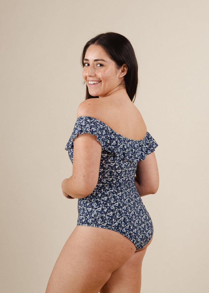 A woman in a Milano Moonflower One-Piece Swimsuit with blue flowers.