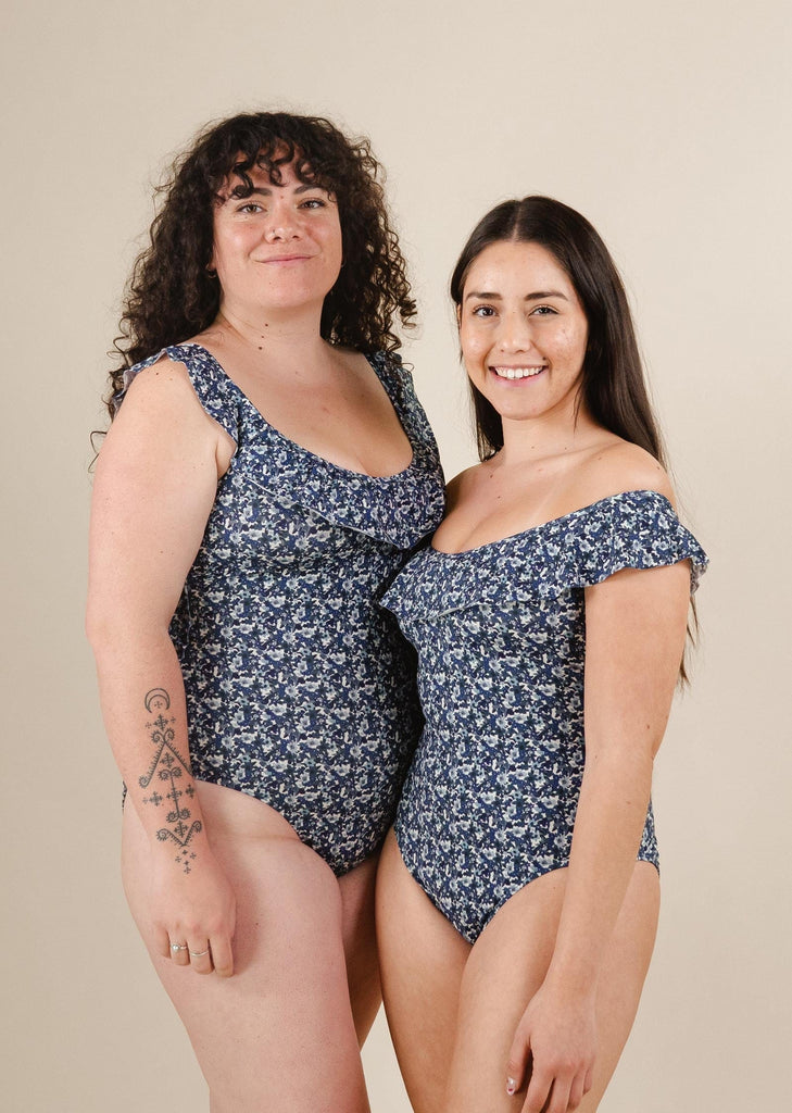 A couple of women standing next to each other wearing the Milano Moonflower One-Piece Swimsuit by mimi and august.