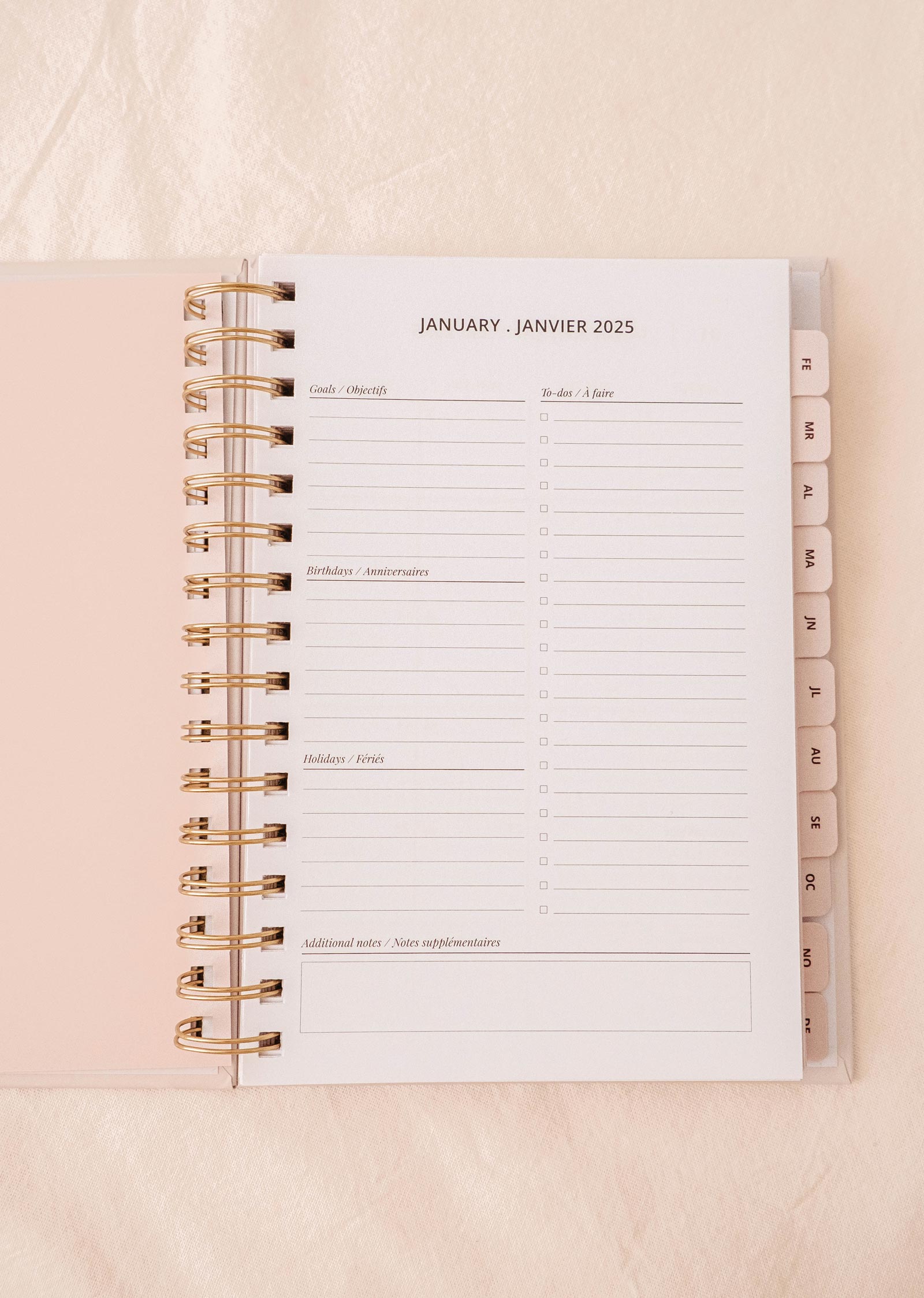 The Fields of Flowers - Agenda 2025 by Mimi & August showcases an open planner displaying a January 2025 page, featuring sections for goals, to-do lists, birthdays, holidays, and notes. Designed with a durable cover and sturdy spiral binding, it promises longevity throughout the year.