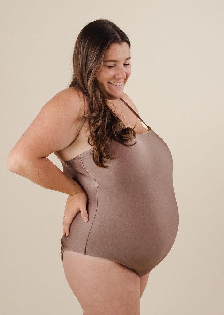 A pregnant woman in a flattering cut Nohea Dunes One-Piece Swimsuit.