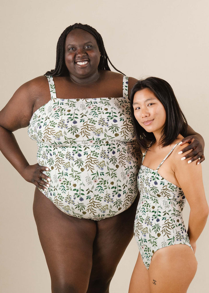 Un couple de femmes se tenant l'une à côté de l'autre dans le maillot de bain une pièce Nohea Herboria de mimi et august.