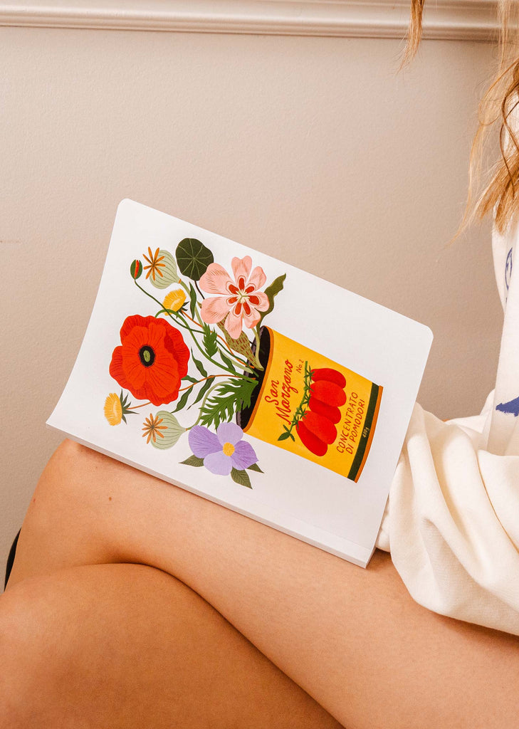 A woman holding a bodil jane notebook with flowers on it.
