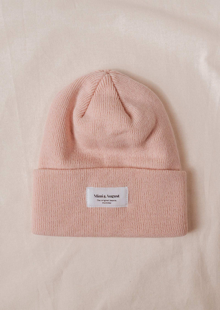 A pale rose beanie with a label on it.