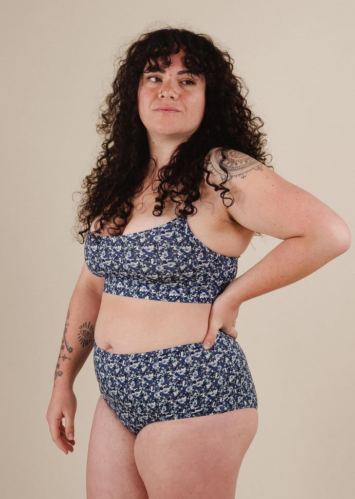 une femme portant le bas de bikini taille haute Paloma Moonflower avec un tatouage sur le bras droit.