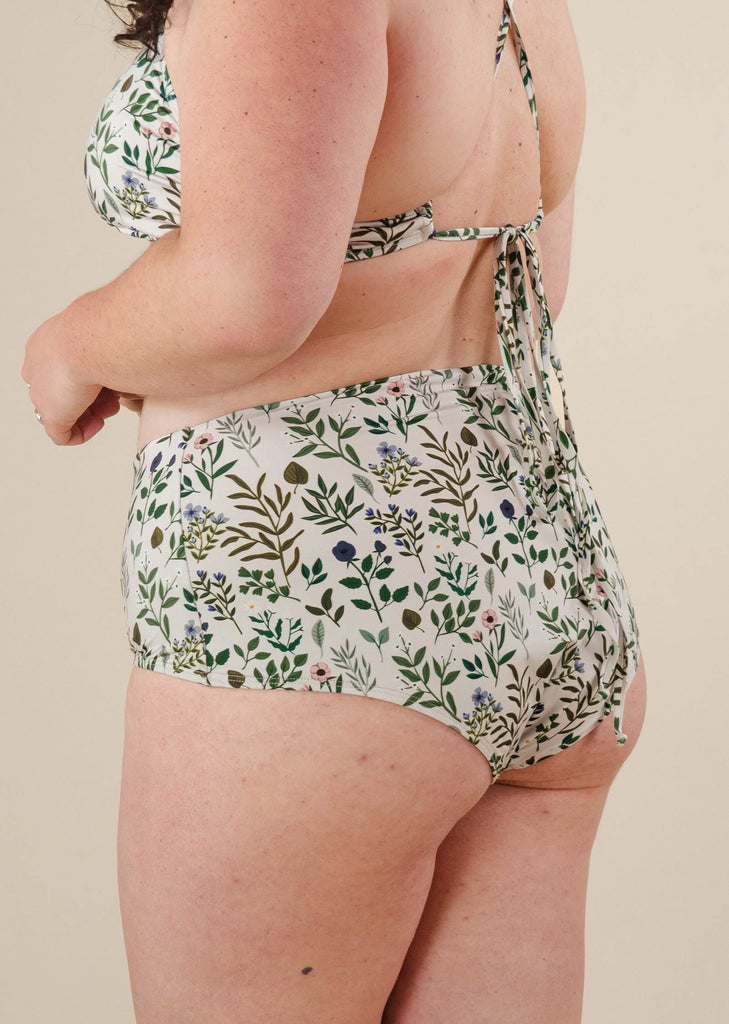 Une femme portant le bas de bikini fleuri taille haute mimi et august.