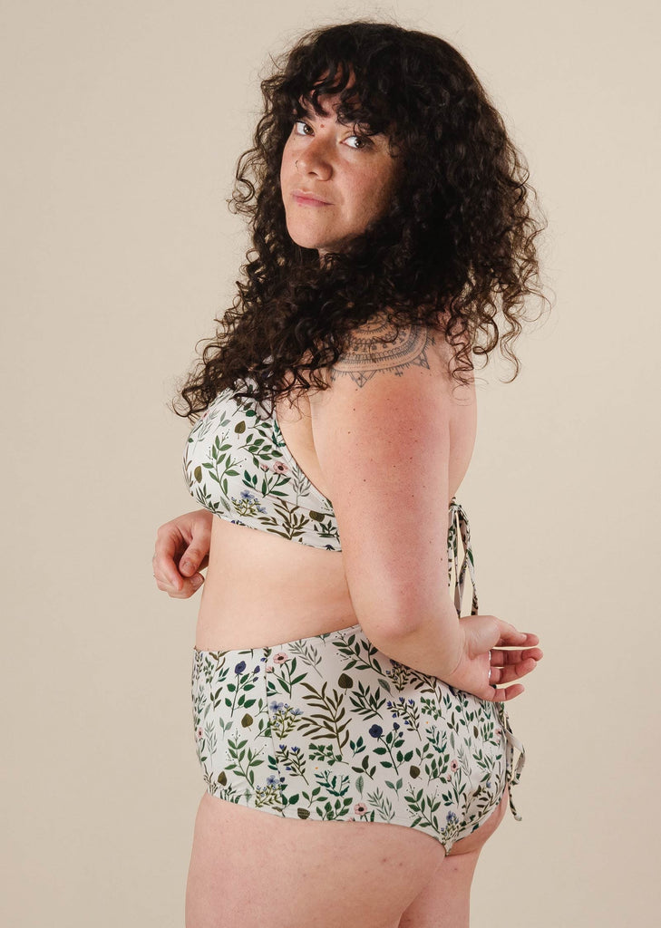 A woman in a Herboria High Waist Bikini Bottom and bikini top posing for a picture.