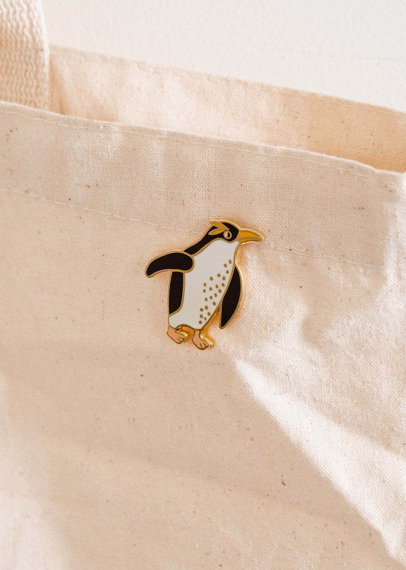 Penguin-themed enamel pin on a tote bag by mimi and august