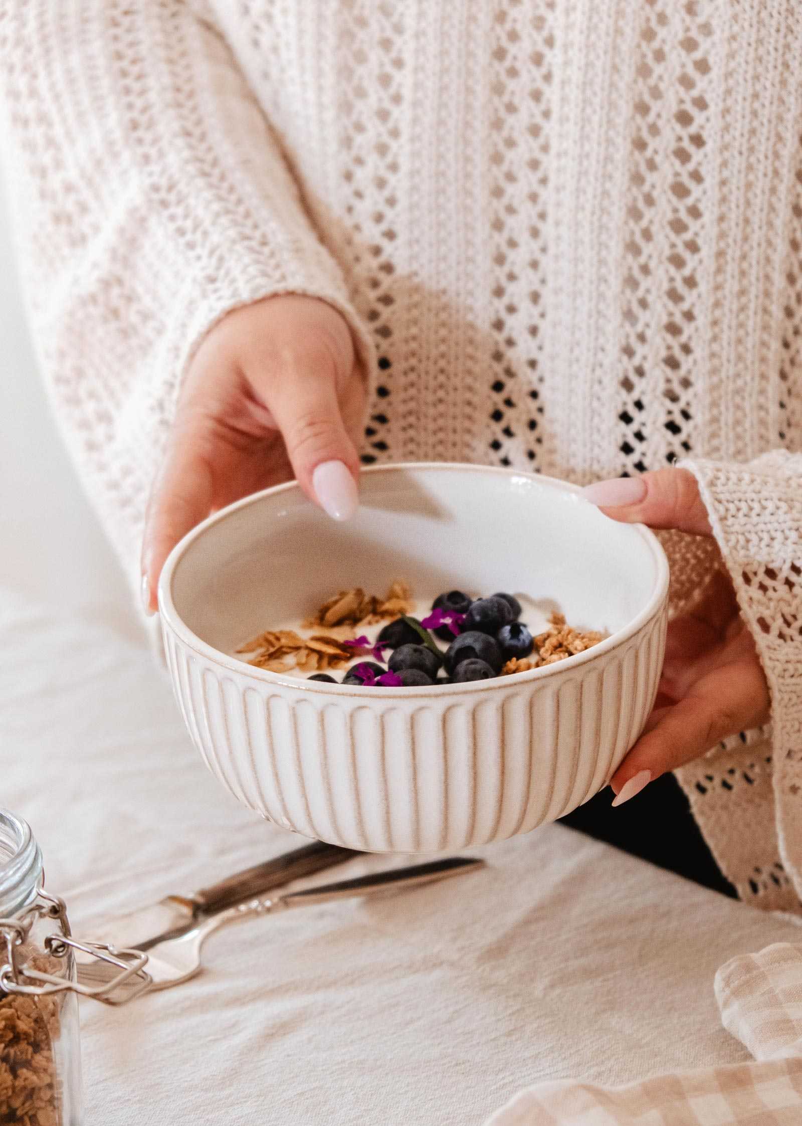 Handmade ceramic bowl with ribbed detailing and cream glaze on table