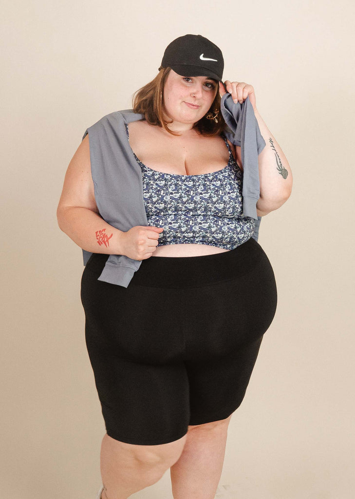 A woman in black shorts by mimi and august with a hat posing for a photo.
