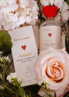 Le spray d'ambiance - Amore de Mimi & August, avec ses motifs floraux roses et blancs sur le flacon et l'emballage, remplit tout espace d'une atmosphère romantique et florale.