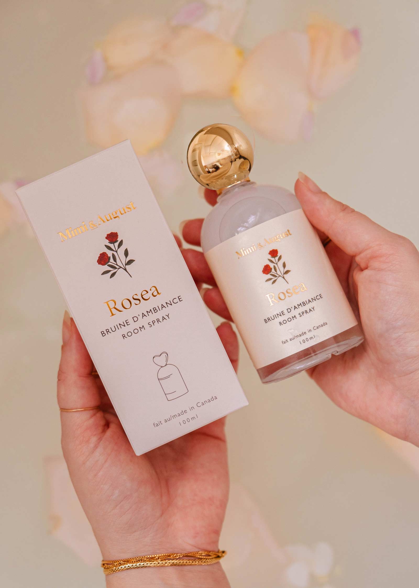 A person holds the Mimi & August Room Spray - Rosea, a citrus floral scent with minimalist floral designs and gold accents—ideal for enhancing any home fragrance collection.
