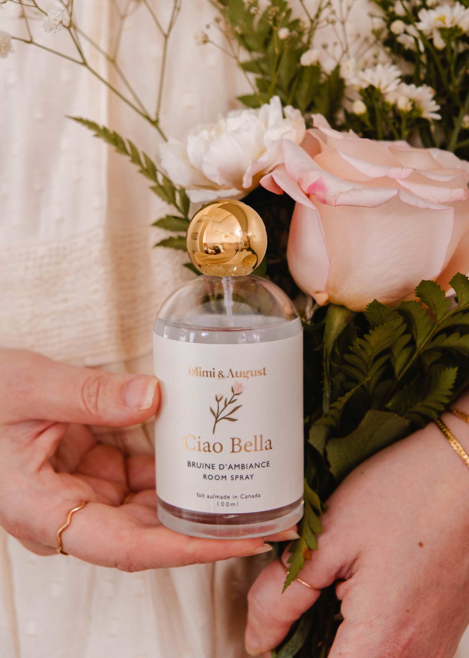 Holding a bouquet in one hand and Mimi & August's Room Spray - Ciao Bella in the other, someone is ready to refresh their space with a floral scent.