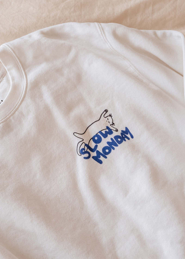 A cozy Slow Monday Sweatshirt with a blue logo on it from Mimi & August.