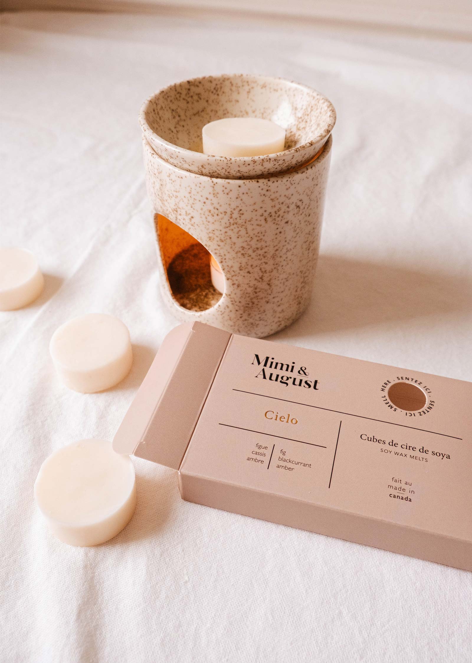 Mimi & August's Soy Wax Melts - Cielo are presented with a ceramic holder, promising a long-lasting aroma. The packaging emphasizes that the product is crafted in Canada from 100% soy wax.