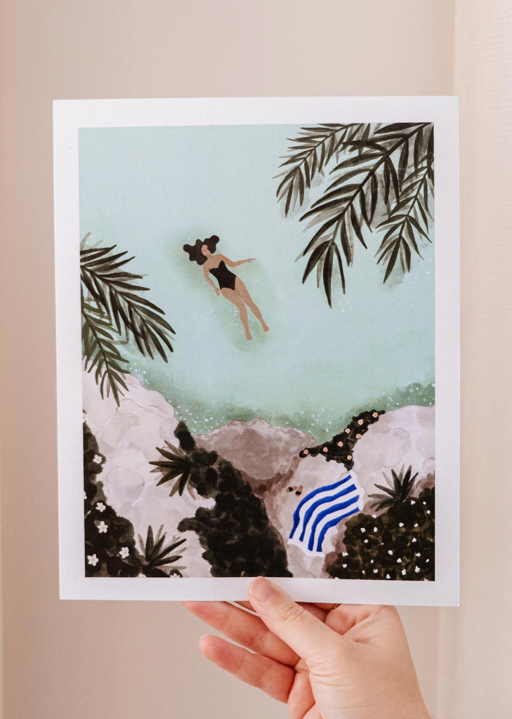 Une main tenant une illustration d'une femme nageant dans l'eau Impression d'art par Mimi & August.