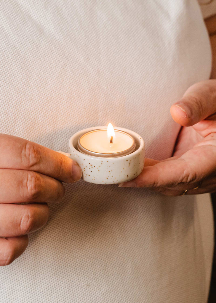 A ceramic Tealight Holder with a woman holding a tea light from Mimi & August.