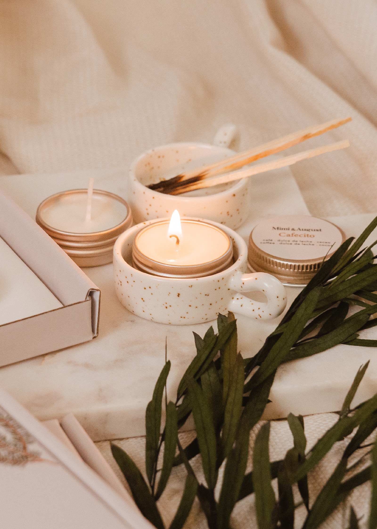 A set of Mimi & August Tealight Holders on a bed with a book and some greenery, exuding rustic charm.