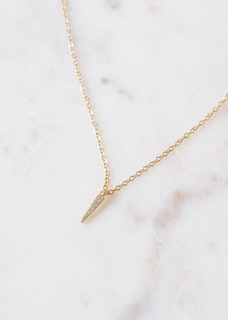 An elegant mimi and august Gold Plated necklace on a marble surface.