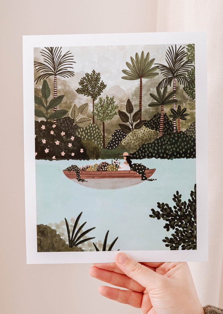 Une impression d'art de Mimi & August capturant la tranquillité naturelle d'un voyage pittoresque, avec une main tenant l'illustration Le lac