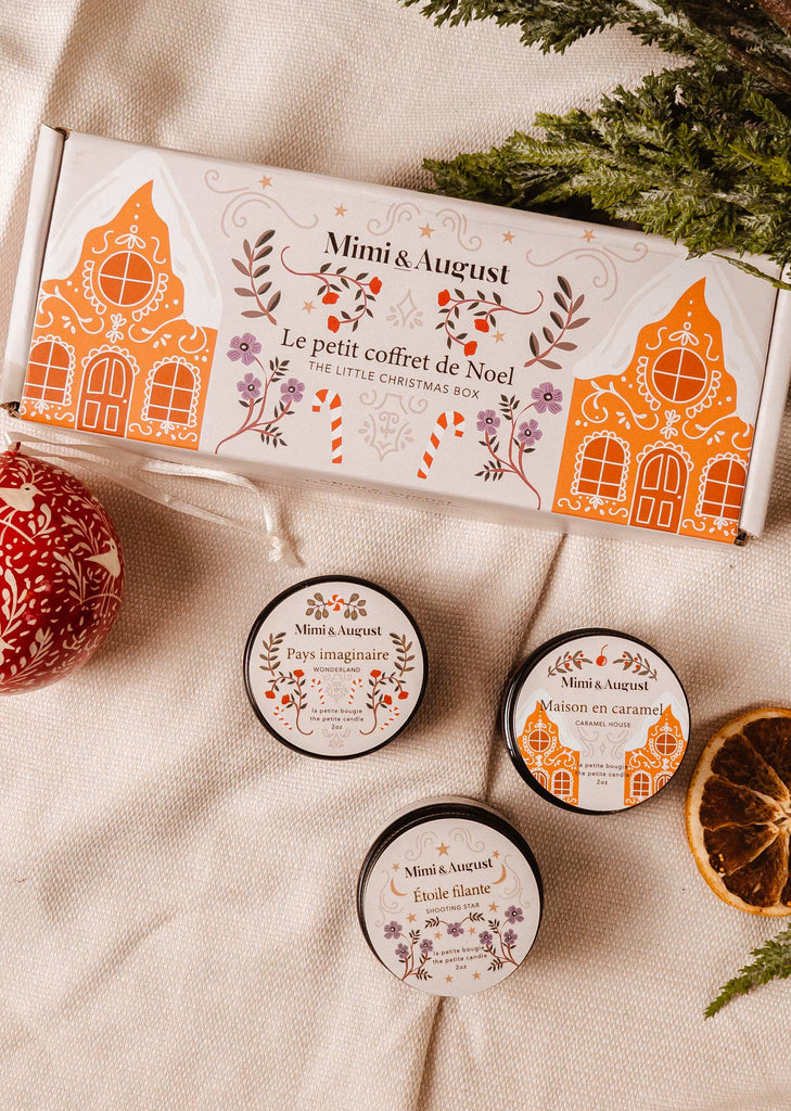 A Mimi & August Little Christmas Box gift set with holiday inspired fragrances and Christmas candles on a table.