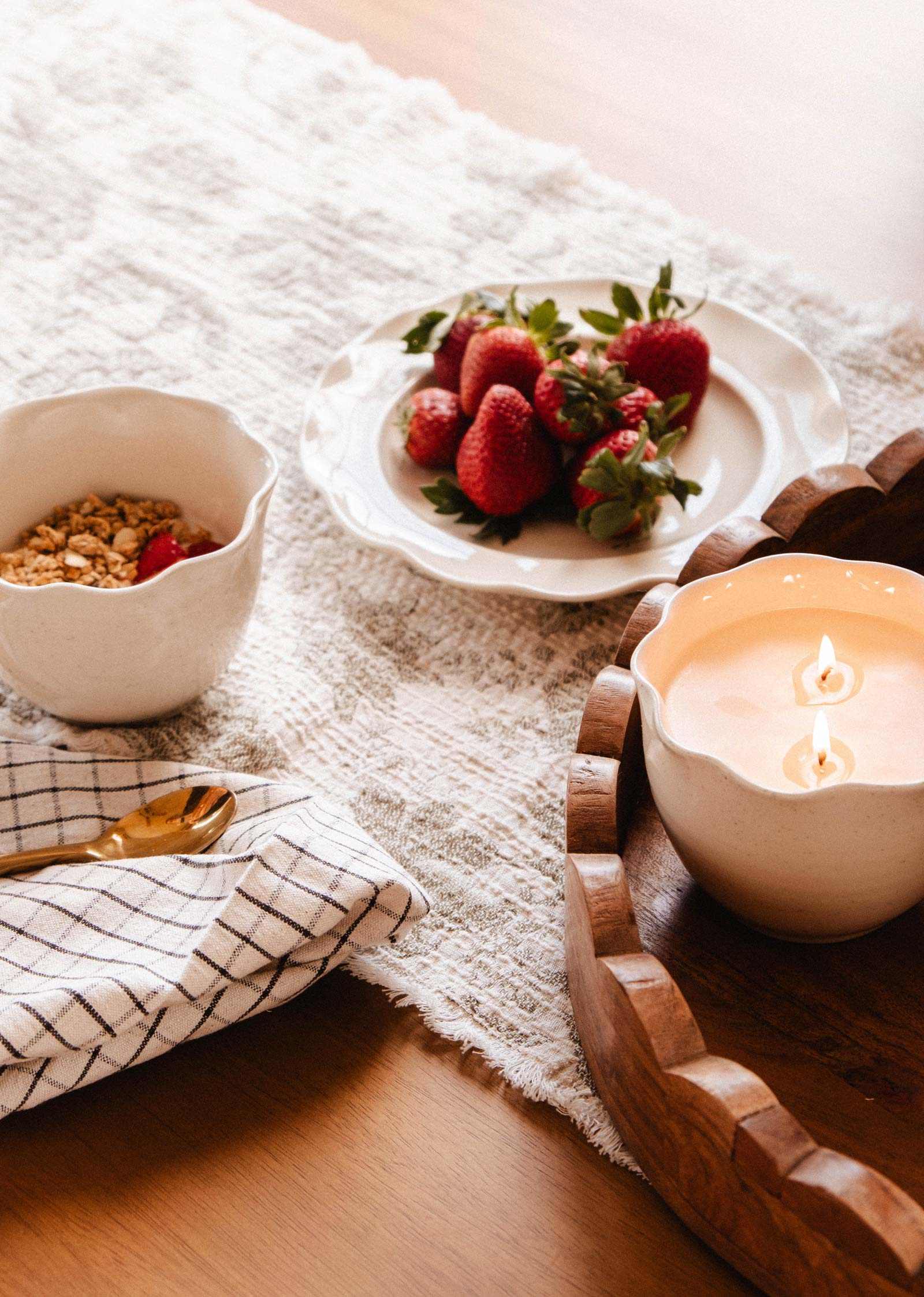 The Petal Bowl Candle by Mimi & August, artfully arranged with granola, fresh strawberries, and a gold spoon on a checkered cloth, makes a thoughtful Mother's Day gift.