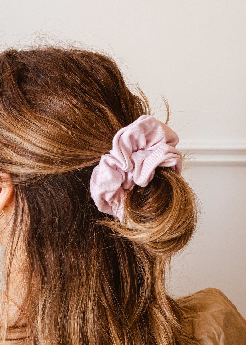 A woman wearing a color velvet blush scrunchie by mimi and august.