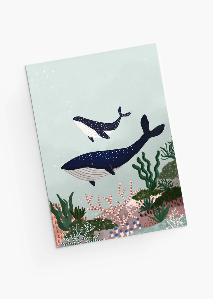 Une peinture numérique de Baleines - Carte de fête des mères, représentant une mère baleine et son baleineau nageant au-dessus d'un récif corallien coloré, sur un fond bleu pâle, parfait pour une carte de vœux de fête des mères par Mimi & August.