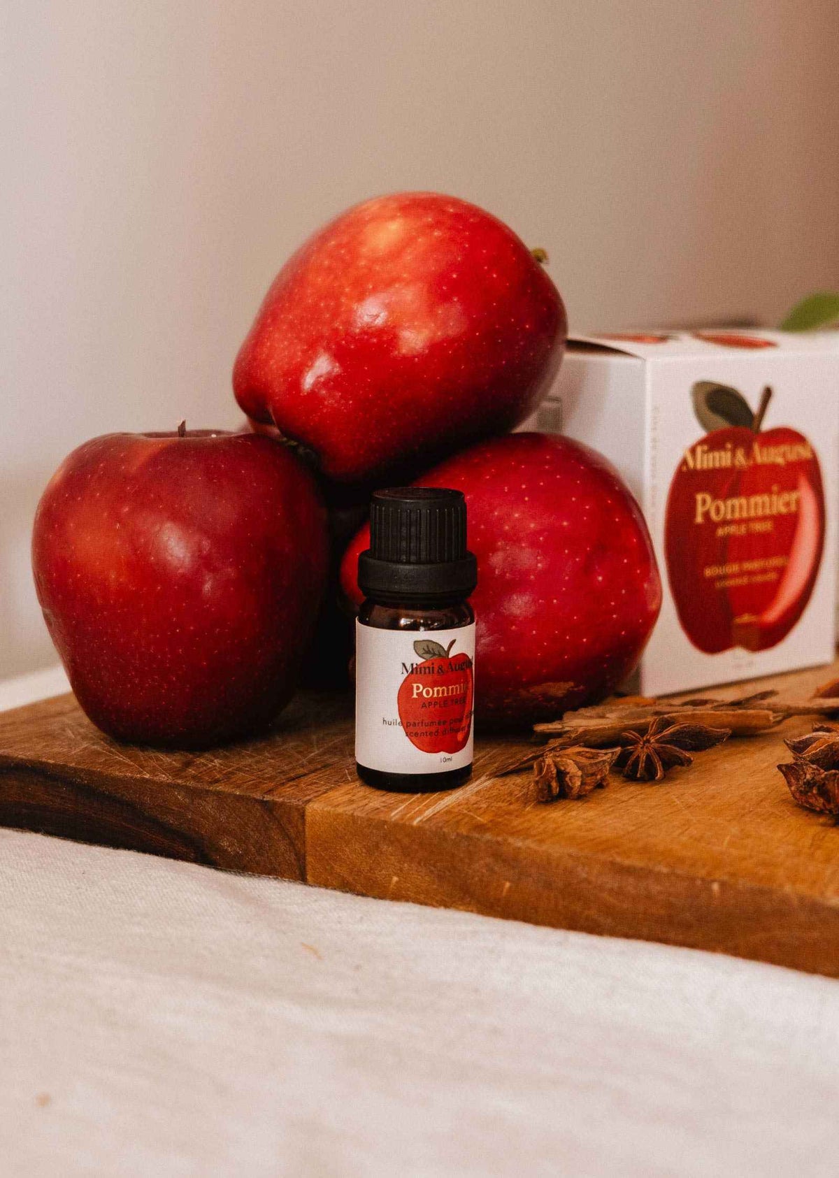 Flacon d'huile parfumée pomme cannelle avec pommes fraîches et bâtons de cannelle sur fond automnal