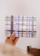 A hand holds a Mimi & August "Build Your Own Discovery Kit" box with a pastel plaid design, featuring natural soy wax candles.