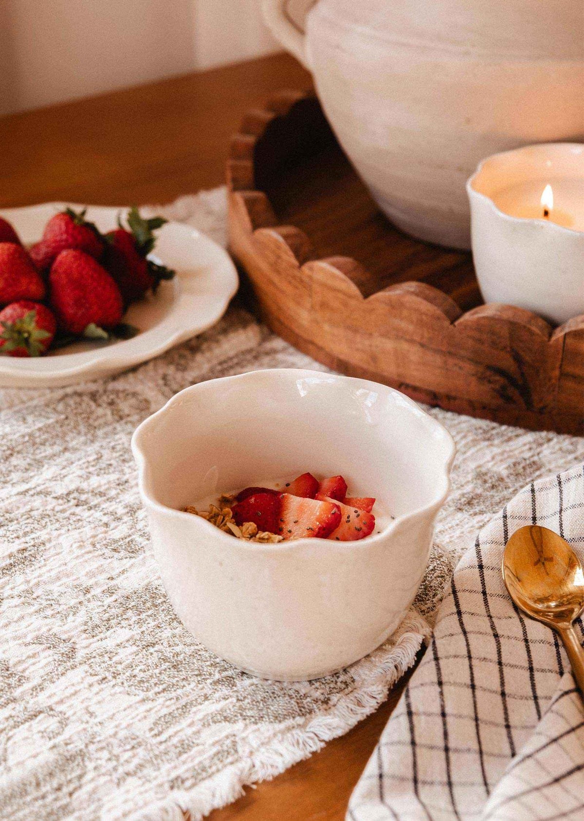 Bougie en céramique crème à glaçure mouchetée, avec rebord festonné en pétales et deux mèches en coton.