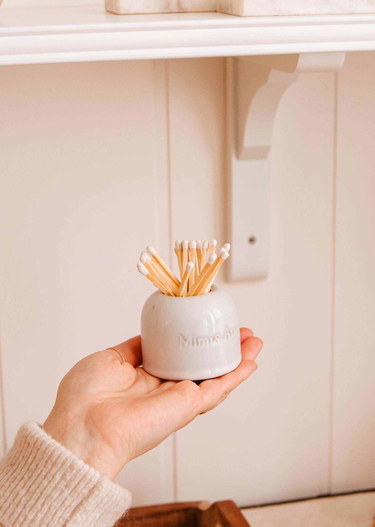 Ceramic match holder in creamy finish with embossed Mimi & August logo and built-in match scratcher