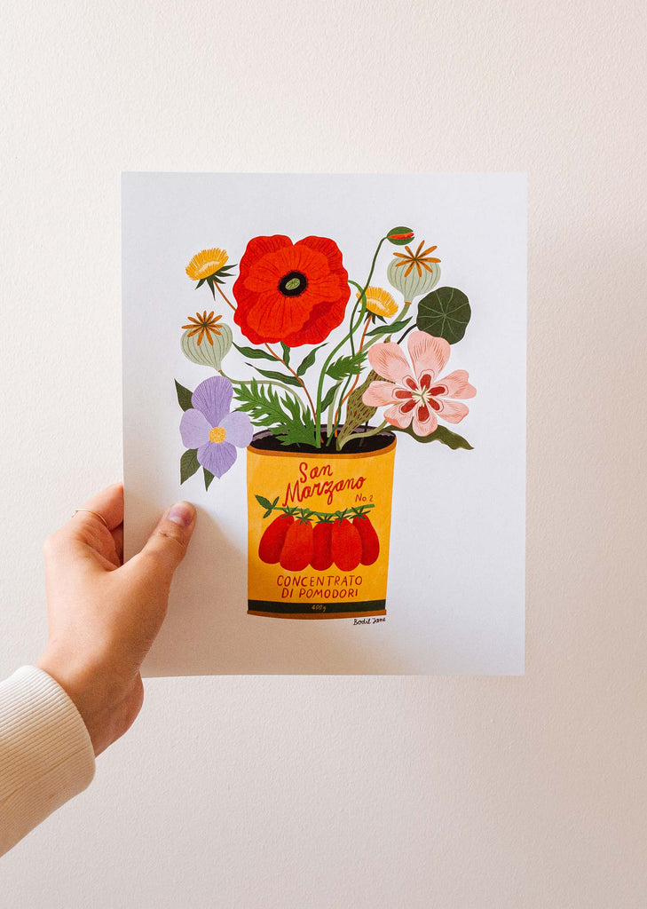 A hand holding an art print of a pot of flowers by Bodil Jane x Mimi and august