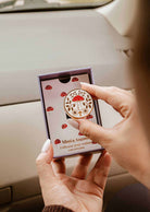 Diffuseur pour voiture Champignon en émail crème et doré, orné d’un motif de champignon rouge, de fleurs et de feuillages.