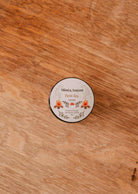 The Mimi & August Petit Feu – 2 oz Soy Candle features a floral tin, coffee scent, and reusable design—perfect for any space.