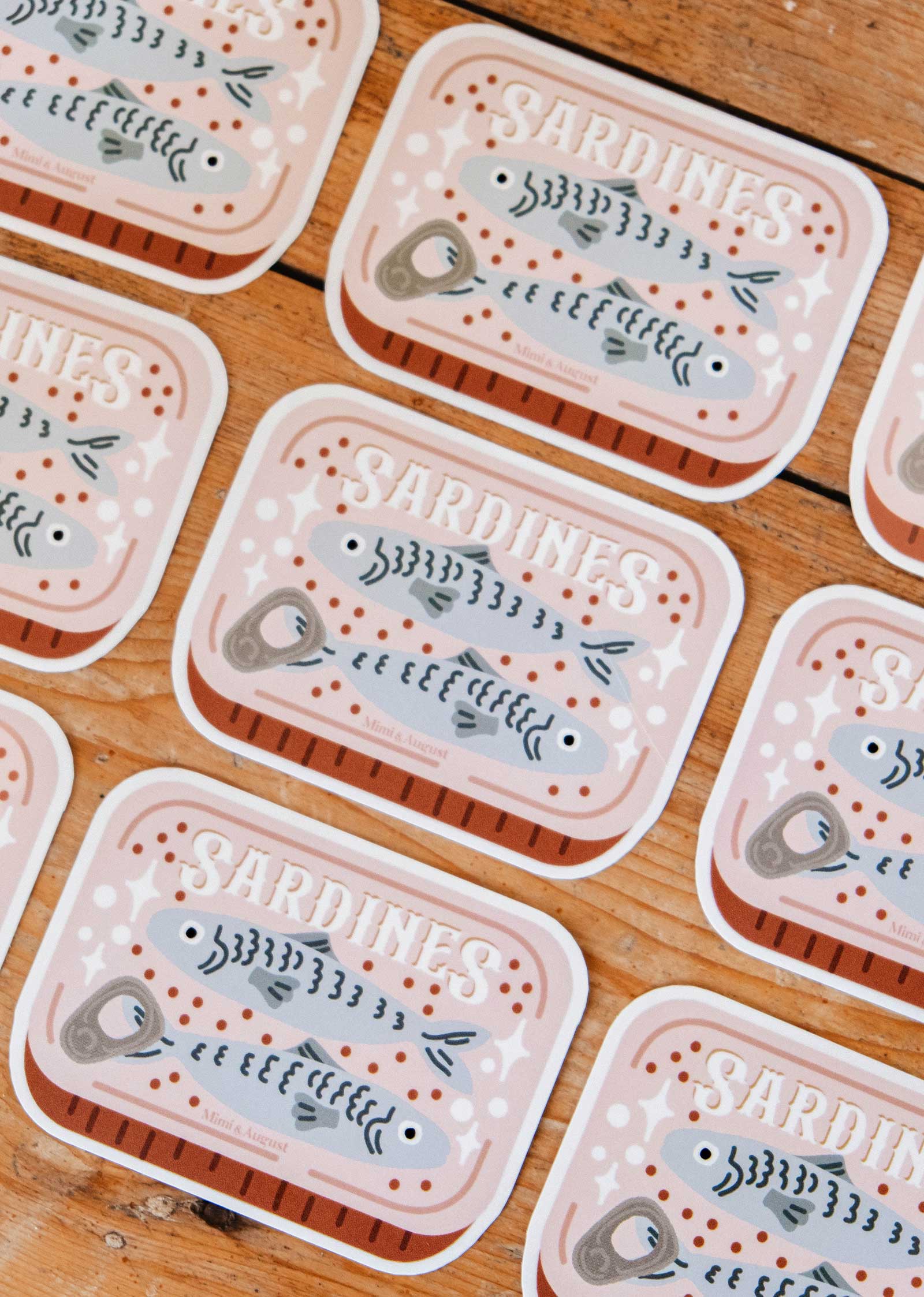 The Cozy Sardines - Vinyl Sticker by Mimi & August is a durable, waterproof sticker featuring three cute sardines in a can labeled "SARDINES," perfect for adding a cozy touch to your items.