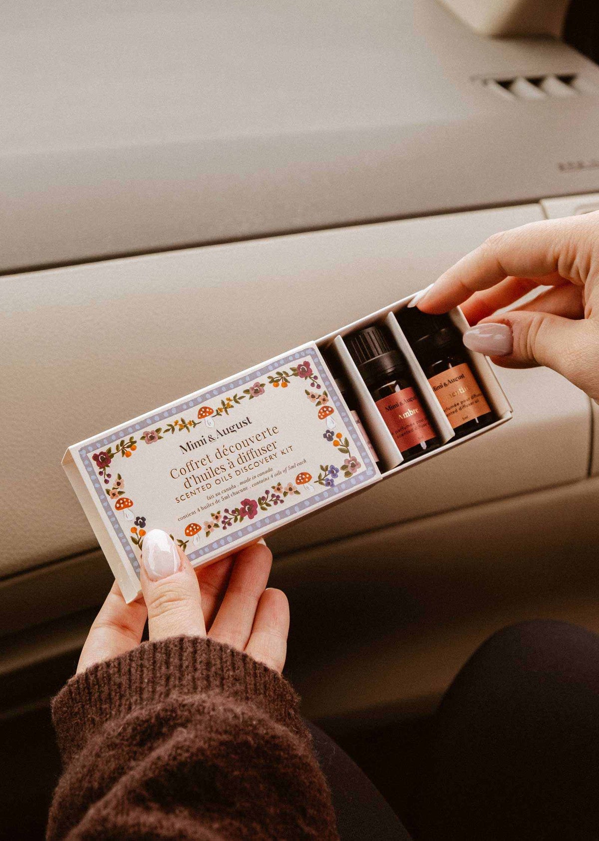 Coffret découverte d’Huiles Parfumées avec quatre petits flacons ambrés et une boîte ornée de motifs floraux automnaux.