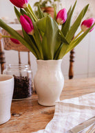 Silhouette Ceramic Vase en céramique crème mouchetée, aux courbes douces et au col ondulé, garnie de tulipes roses.