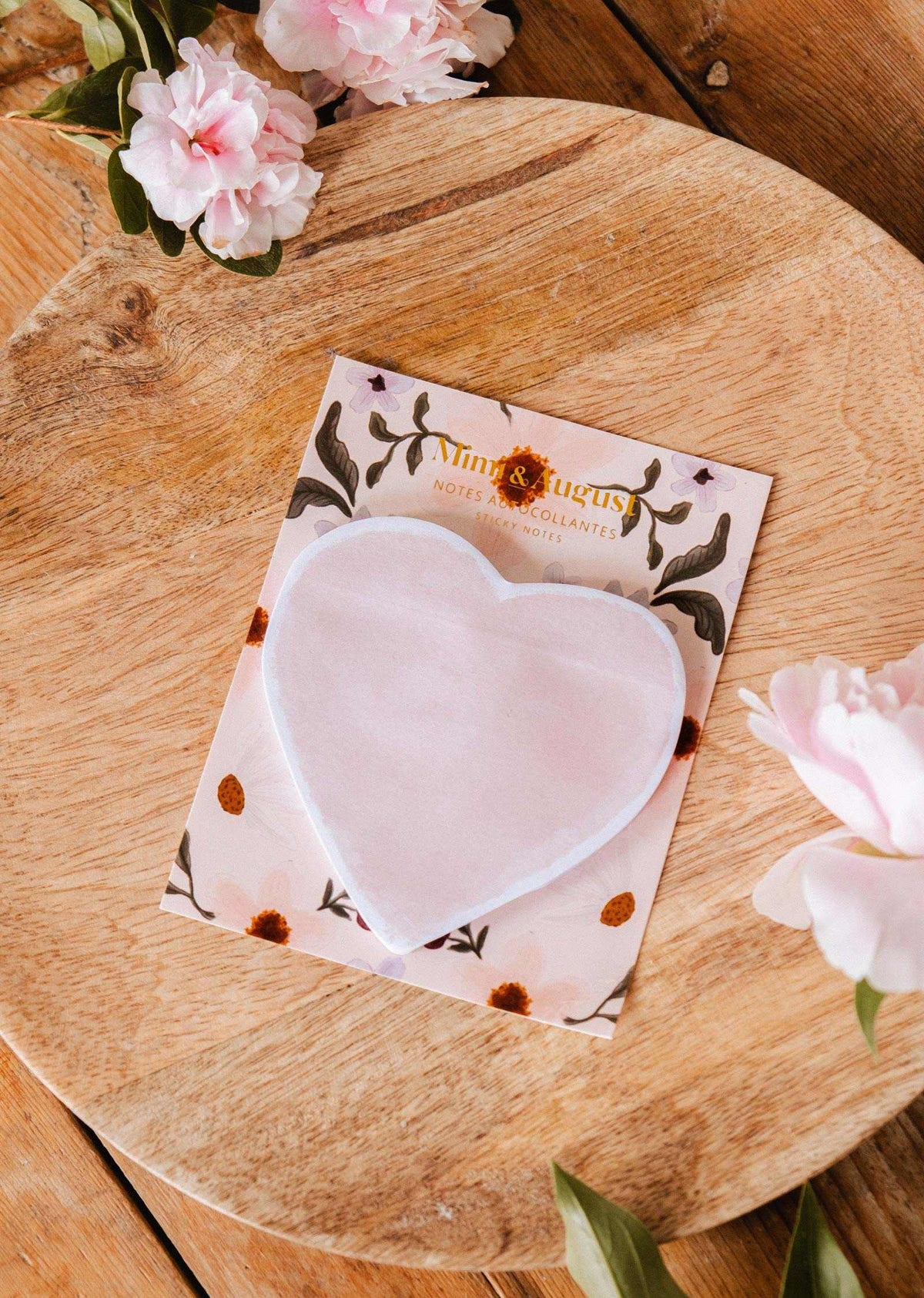 The Soft Heart - Sticky Notes by Mimi & August rest on a floral backing card atop a round wooden board, with pink flowers nearby.