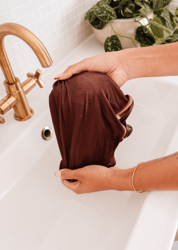 a woman is washing a bathing suit in a sink using a eco-friendly soap