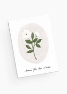 The White Flower Mother's Day Greeting Card from Mimi & August is crafted from recycled paper, featuring a white flower and green leaves illustration with the French greeting "Bonne fête des mères," conveying the delicate charm of pastel blooms.
