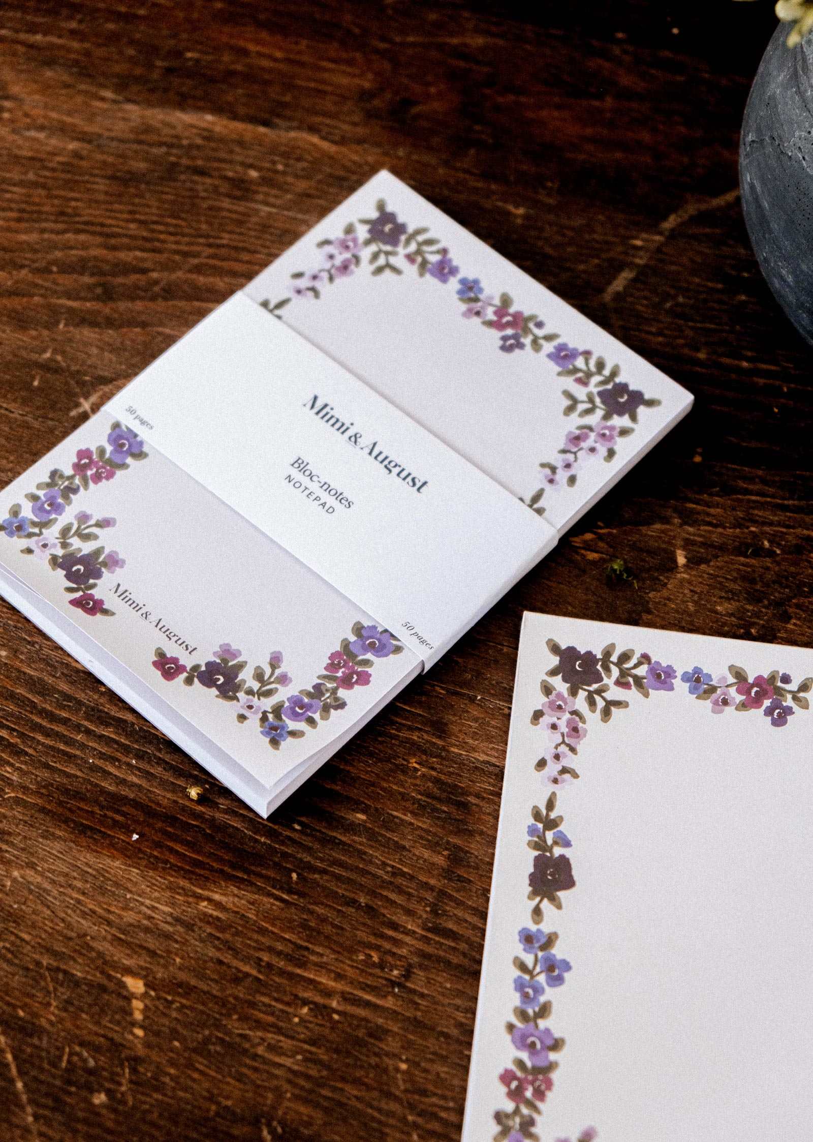 Wildflowers floral notepad by Mimi & August shown as a stack with a loose sheet, purple and green floral illustrations on wood.