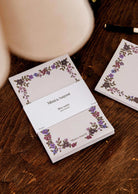 Wildflowers floral notepad by Mimi & August on a wooden surface beside a matching illustrated note card and a pen.
