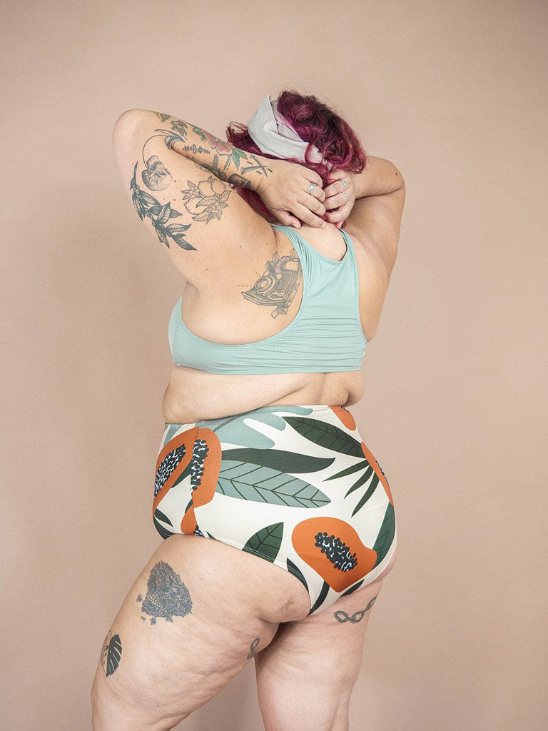 A woman in a Mimi & August Bermudes Papaya Extra High Waist Bikini Bottom with tattoos posing.