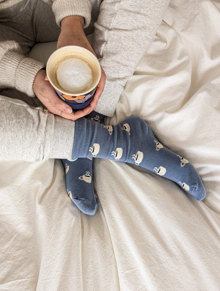 Boire un café au lait au lit avec des chaussettes en coton bleu. 
