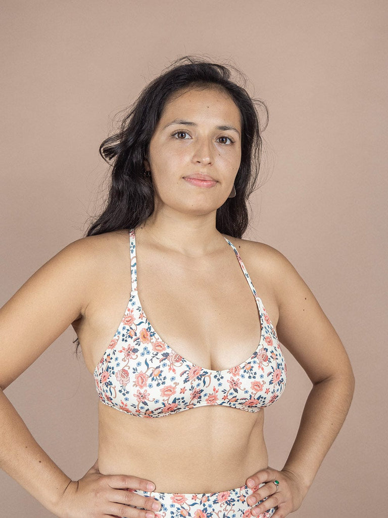A woman in an adjustable floral Chichi Amour Bralette Bikini Top posing for a photoshoot showcasing a new addition to her Mimi & August bikini collection.