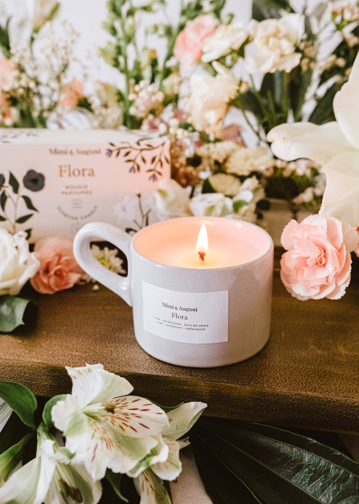 A Flora - Reusable Candle with roses and a floral scent on a wooden table by Mimi & August.