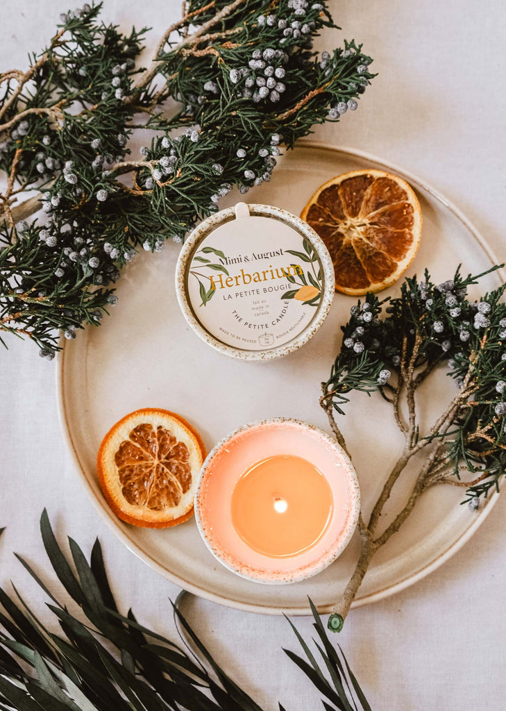 A plate with oranges and eucalyptus leaves, emitting a spring scent, featuring the Mimi & August Herbarium - Reusable Candle.