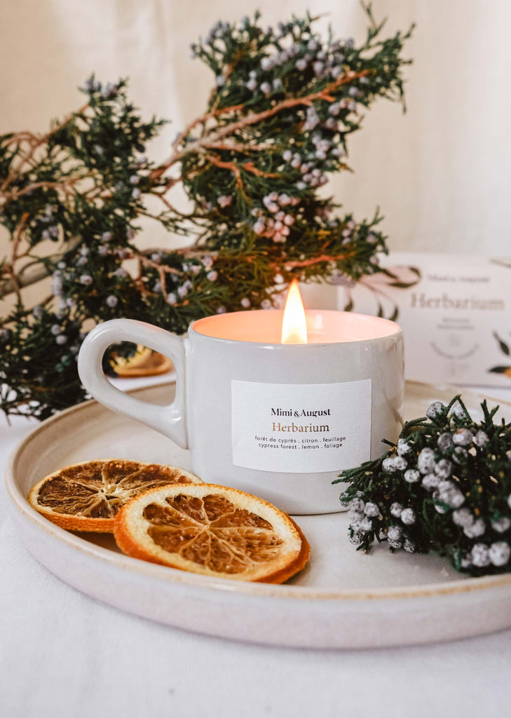 A Mimi & August Herbarium - Reusable Candle is surrounded by orange slices on a plate.