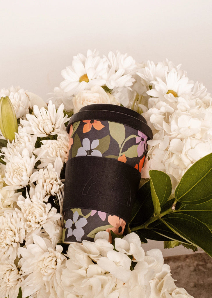 gobelet noir réutilisable sur un bouquet de fleurs blanches