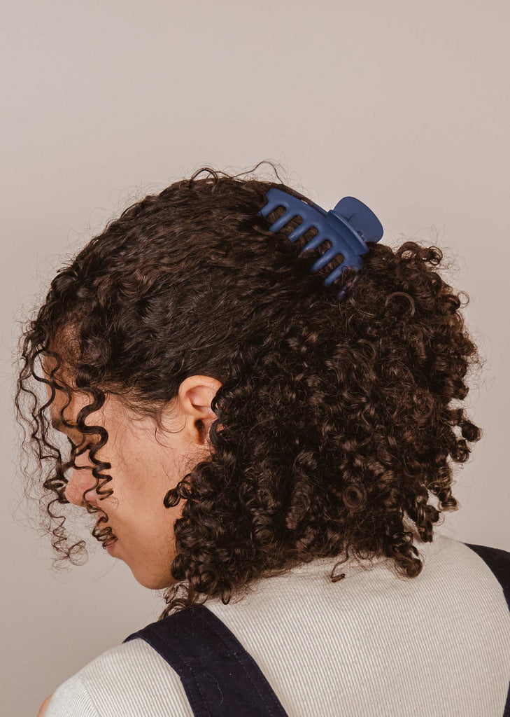 pince à cheveux bleu matte avec de longues griffes qui soutiennent les cheveux longs et bouclés
